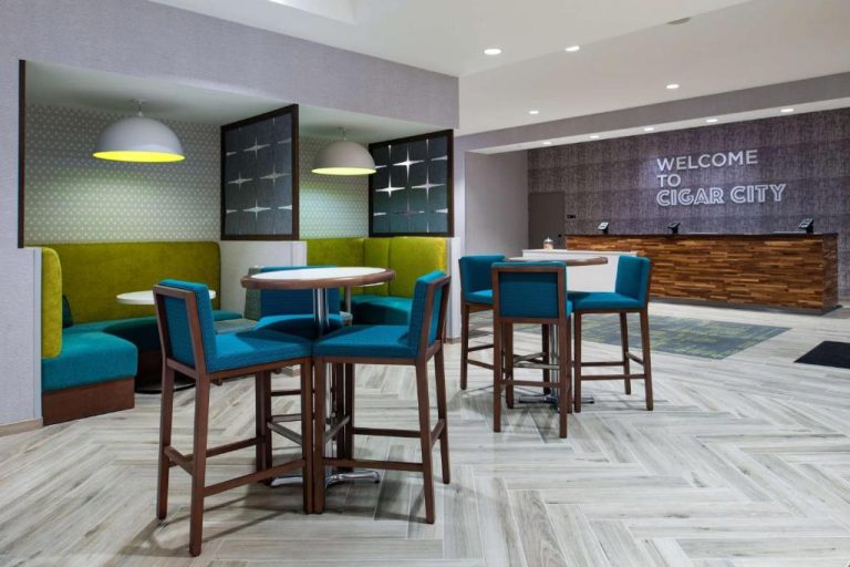 Lobby moderno con recepción y área de descanso en Home2 Suites by Hilton Tampa Downtown Channel District
