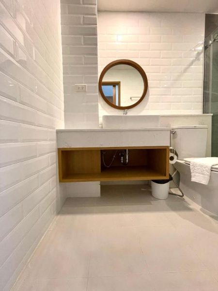 Baño moderno con lavabo empotrado y espejo redondo de madera en Baannalin Hometel