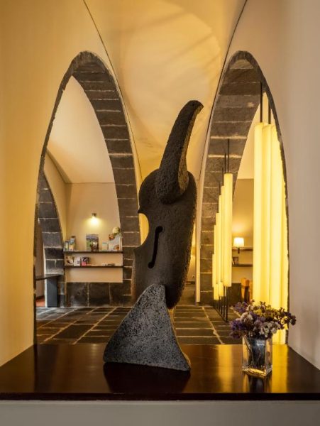 Escultura de piedra volcánica en el lobby del Hotel Do Colegio con arcos de basalto y decoración artística