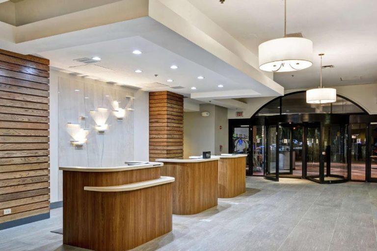 Recepción moderna con mostradores de madera del Embassy Suites by Hilton Orlando Downtown