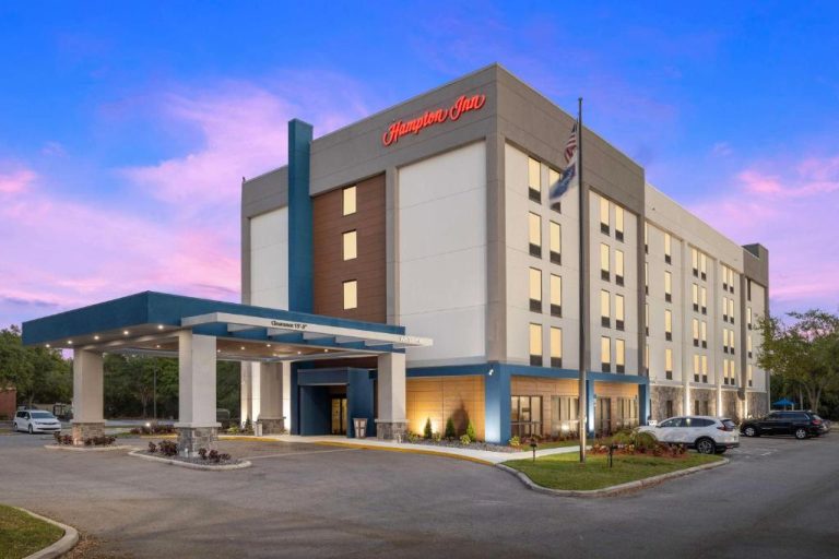 Fachada exterior iluminada del Hampton Inn Tampa Veterans Expressway al atardecer con entrada cubierta