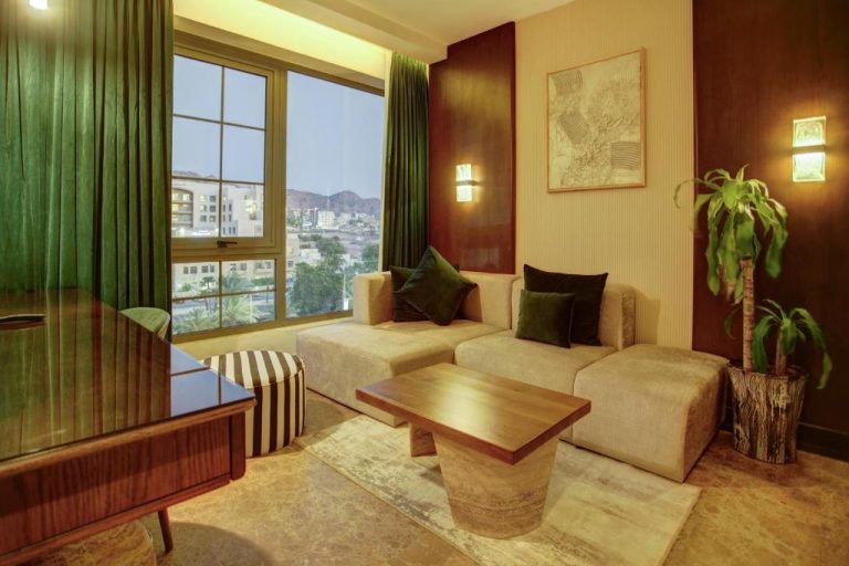Salón elegante de suite en Bratus Hotel con sofá, mesa de madera y ventanal con vistas a la ciudad