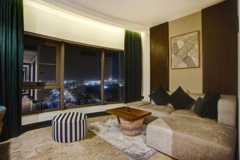 Salón elegante con sofá y vistas panorámicas nocturnas de la ciudad en Bratus Hotel