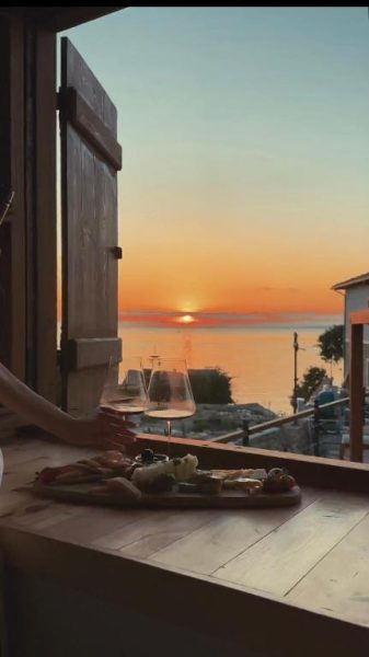 Terraza con tabla de quesos y copas de vino con vistas al atardecer sobre el mar en 6 Rooms By Zula