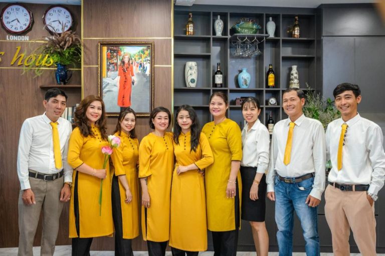 Equipo de recepción del Hannah House Hoi An con uniformes amarillos tradicionales vietnamitas en el lobby