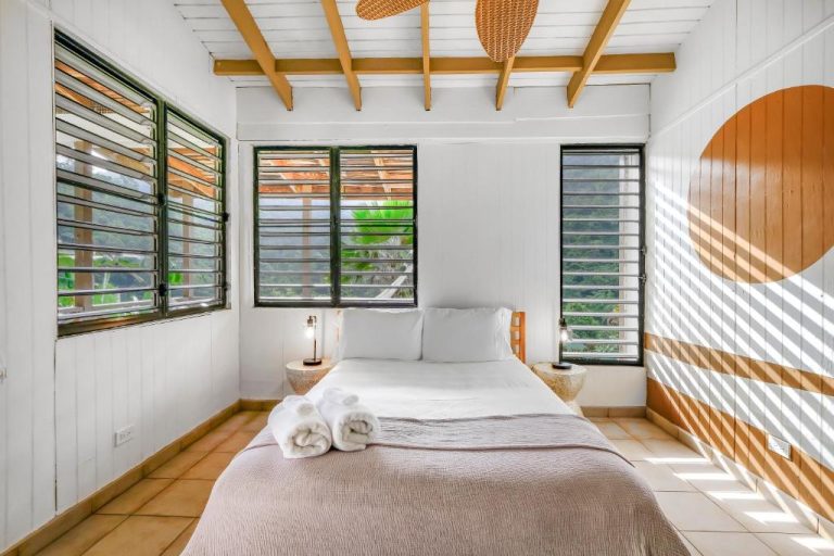 Habitación doble con ventanas de persianas y vistas a vegetación tropical en Casa Grande Mountain Retreat