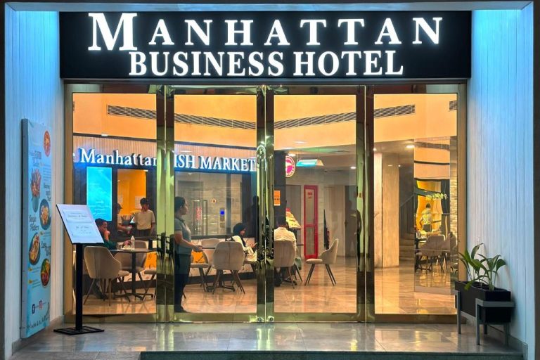 Entrada principal y recepción iluminada del Manhattan Business Hotel en Male, Maldivas