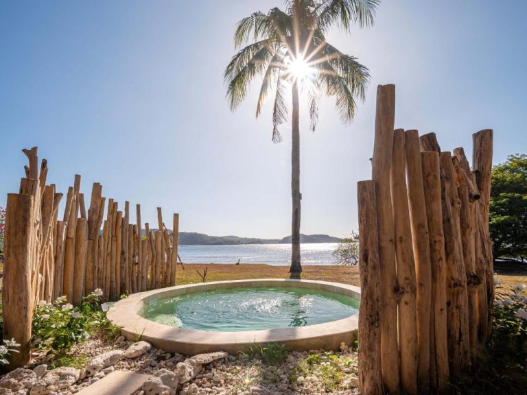 Piscina privada circular con palmera y valla de madera frente al mar en Bleu Mathis Gili Asahan