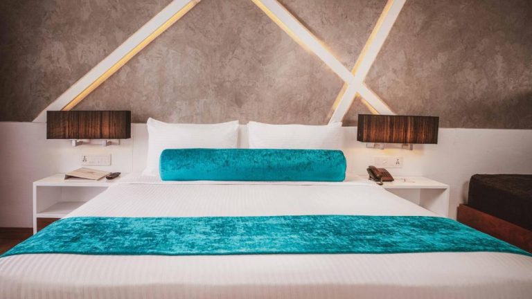 Habitación de lujo con cama king size y decoración turquesa en Camelot Beach Hotel