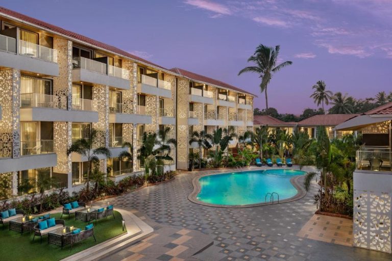 Piscina exterior con tumbonas y jardines tropicales del Hyatt Place Goa Candolim al atardecer