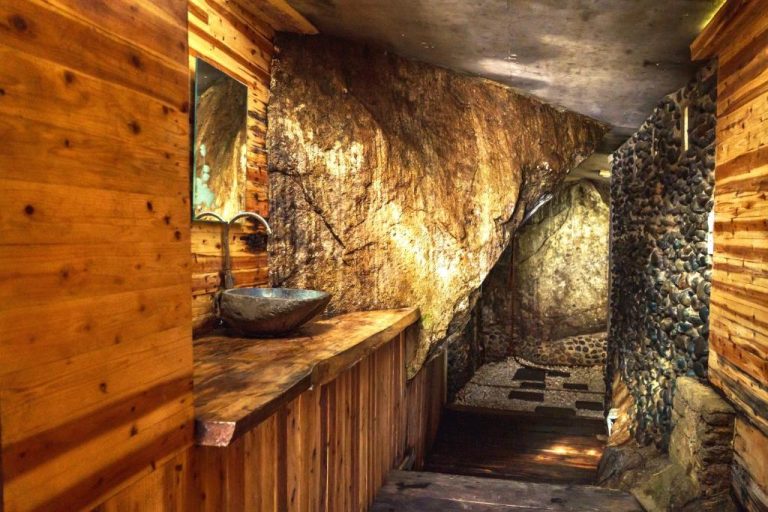 Baño rústico con paredes de roca natural y lavabo de piedra en Ricky's Beach House