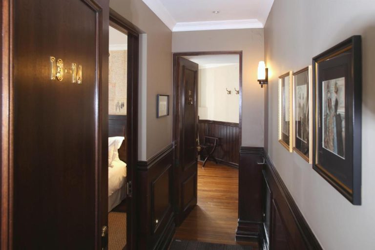 Pasillo elegante con paneles de madera oscura y cuadros enmarcados del Hotel Boutique Castillo Rojo