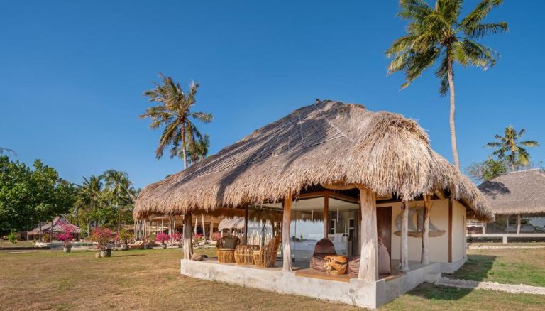 Bungalow con techo de paja y terraza tropical en Bleu Mathis Gili Asahan rodeado de palmeras