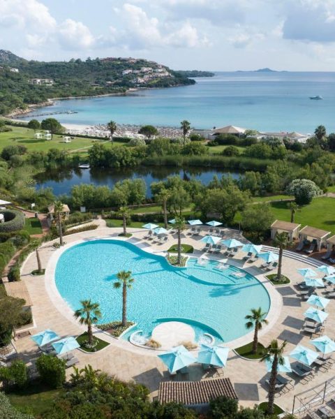 Vista aérea de la piscina exterior con sombrillas del Abi d'Oru Sardinian Beach Resort & Spa en Cerdeña