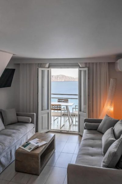 Salón con sofás y balcón con vistas al mar en Belvedere Suites, habitación luminosa y elegante
