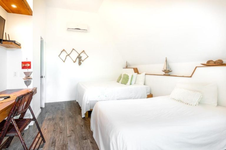 Habitación doble con dos camas blancas y decoración náutica en Punta Rucia Lodge Hotel Boutique & Spa