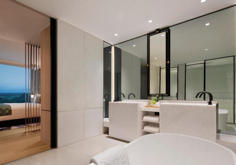 Baño de lujo con bañera exenta y doble lavabo de mármol en el Taj The Trees Mumbai