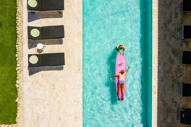 Vista aérea de la piscina con tabla de surf rosa en El Encuentro Surf Lodge