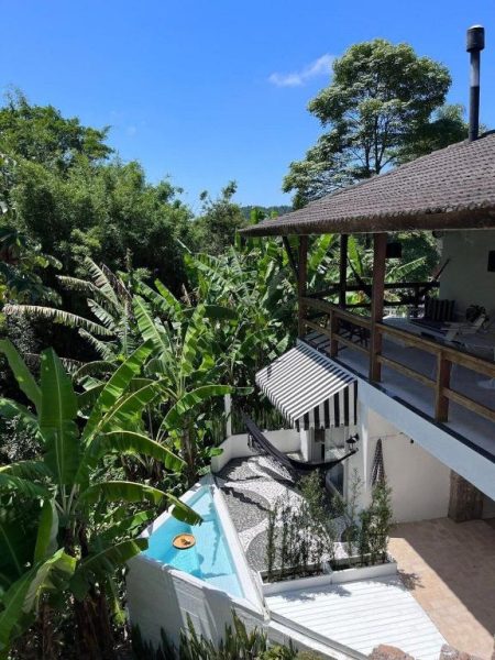 Piscina privada con terraza y vegetación tropical en CasaIvan, rodeada de palmeras y jardín