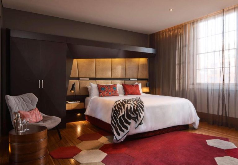 Habitación de lujo con cama king size y decoración elegante en tonos rojos del QT Sydney