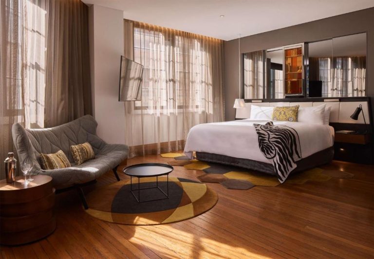 Habitación deluxe con cama king, suelo de madera y decoración ecléctica en el hotel QT Sydney