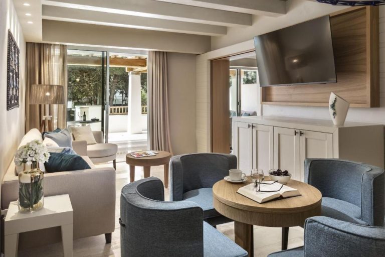 Elegante salón de suite con sillones azules, mesa de madera y terraza exterior en Hotel La Bisaccia