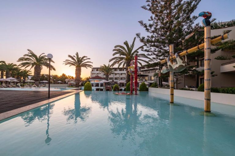 Piscina exterior con esculturas decorativas y palmeras al atardecer en D'Andrea Mare Hotel