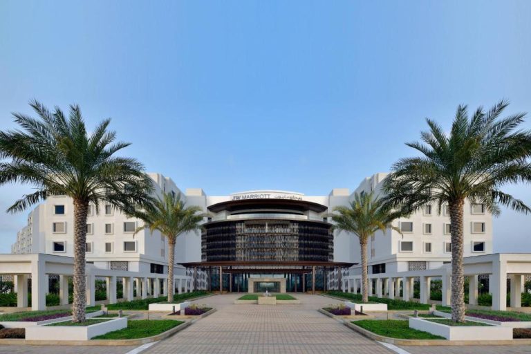 Fachada y entrada principal del JW Marriott Hotel Muscat con palmeras y jardines