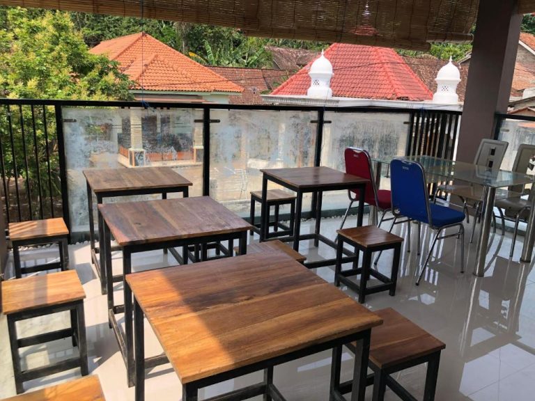 Terraza exterior con mesas y sillas de madera en L'Javas Villas con vistas al vecindario