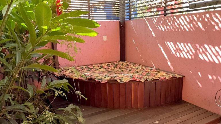 Jacuzzi exterior de madera con cubierta floral en terraza privada de Pousada Vila Rosada
