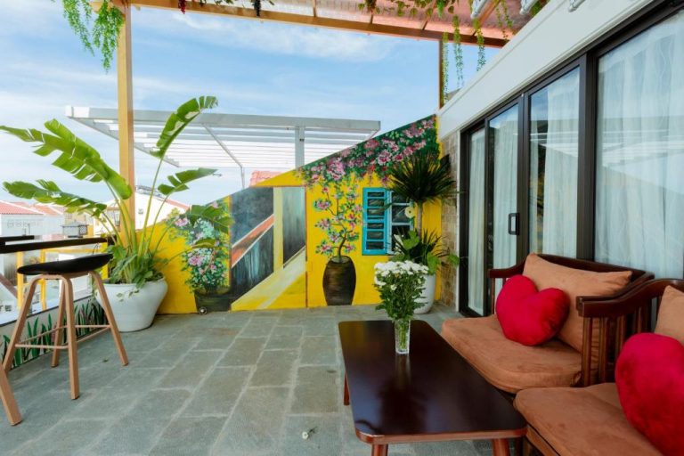 Terraza exterior con mural artístico colorido y zona lounge del Hannah House Hoi An