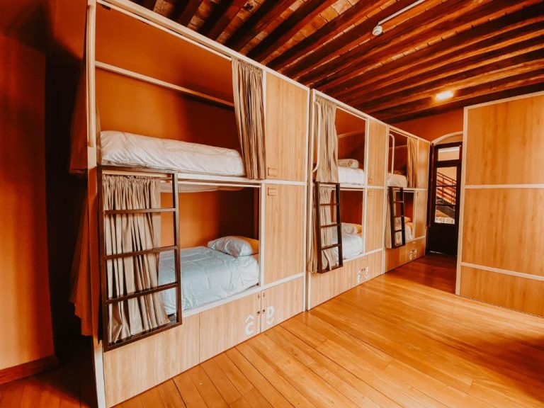Habitación compartida con literas de madera y cortinas privadas en Viajero Quito Hostel