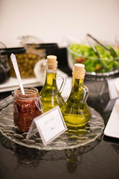 Estación de ensaladas con aceite de oliva y salsa picante en el buffet del Dweik Hotel 2