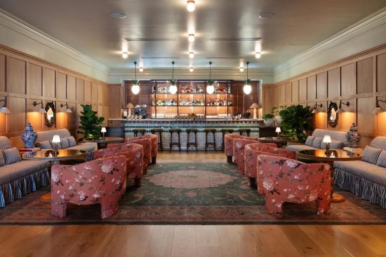 Elegante bar y sala lounge del Palihouse Hyde Park Village con sillones florales y barra de cócteles
