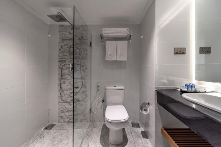 Baño moderno con ducha de lluvia y sanitarios blancos en Premium Inn Mombasa City