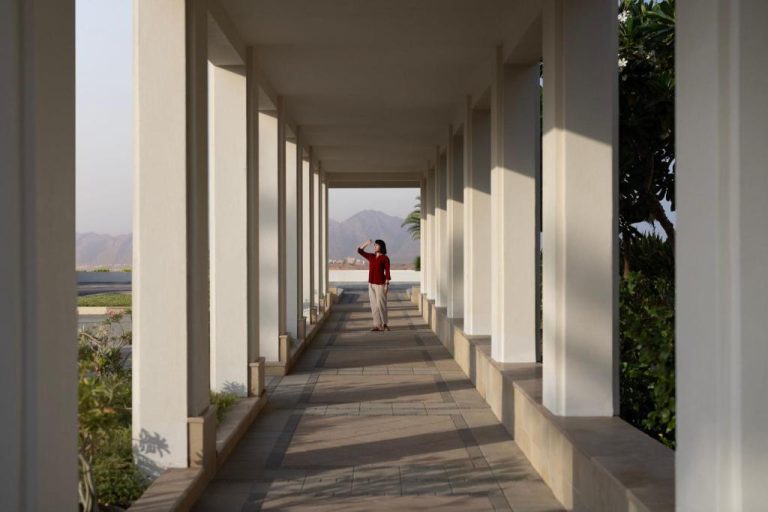 Corredor exterior con columnas blancas y vistas a las montañas del JW Marriott Hotel Muscat