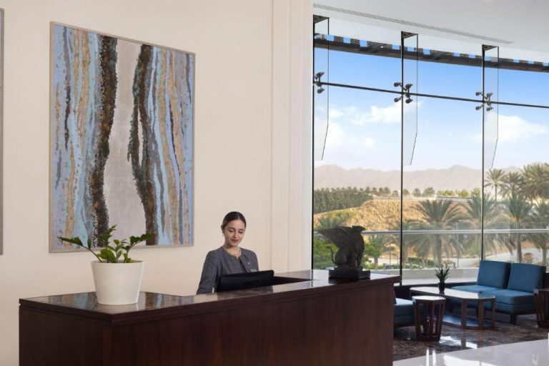 Recepción elegante del JW Marriott Hotel Muscat con vistas panorámicas al desierto y palmeras