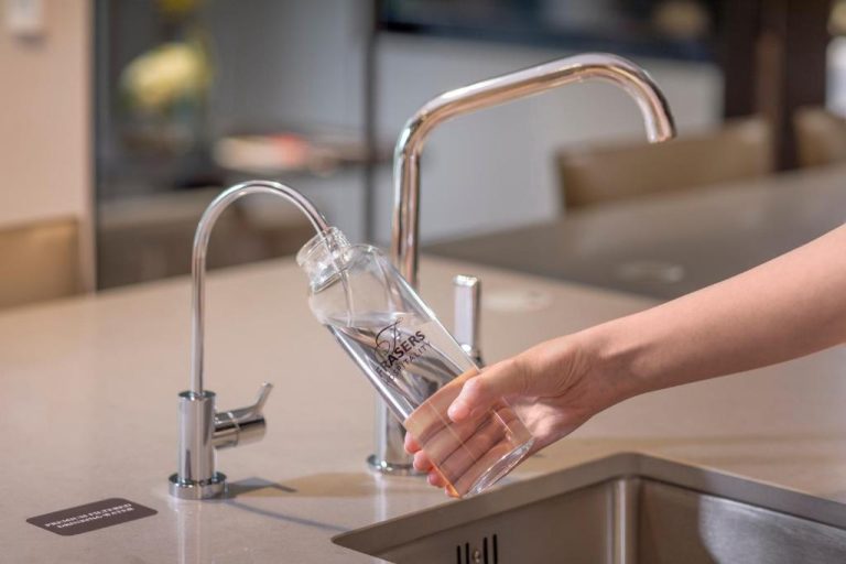 Rellenando botella de cristal Frasers Hospitality con agua filtrada premium en Fraser Residence River Promenade Singapur