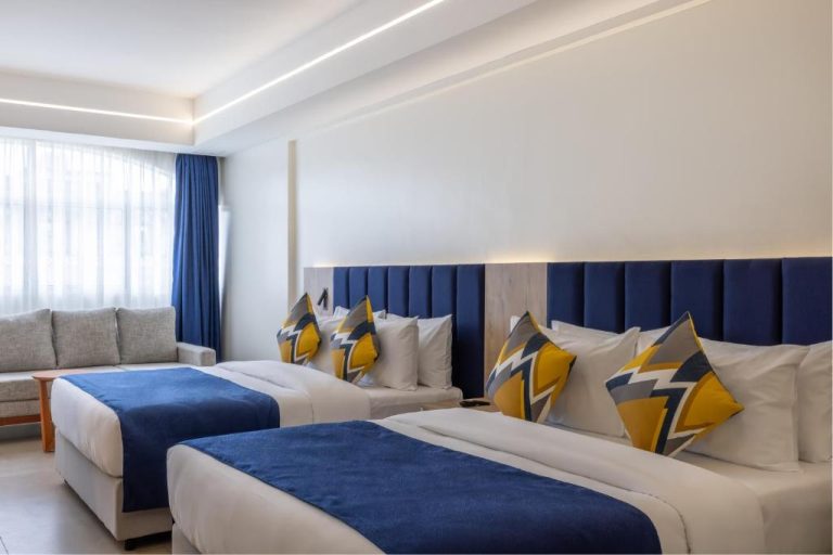 Habitación twin con cabeceros azules y decoración en dorado del Premium Inn Mombasa City