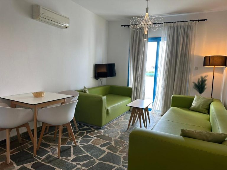 Salón luminoso con sofás verdes y mesa de comedor en Tasmaria Aparthotel