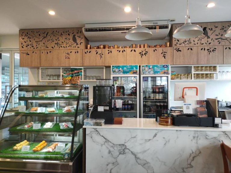 Cafetería del Park 38 Hotel con mostrador de mármol, vitrina de repostería y neveras de bebidas