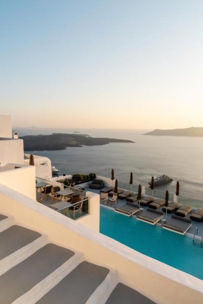 Piscina infinita con tumbonas y vistas a la caldera volcánica de Santorini en Belvedere Suites