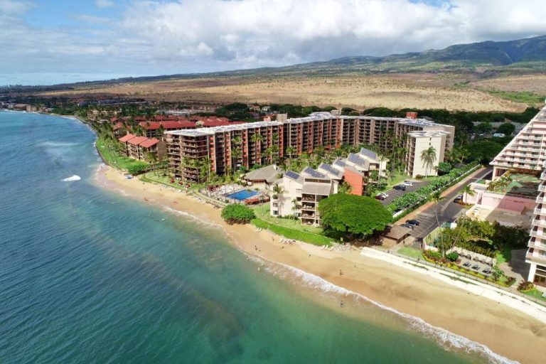 Vista aérea del Aston Kaanapali Shores con playa de arena, piscina exterior y palmeras en Maui, Hawái