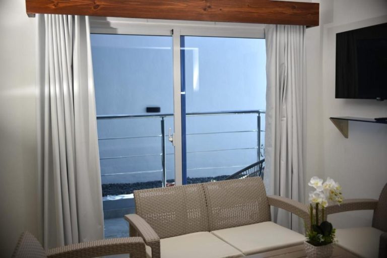 Habitación con sofá de ratán y balcón con vistas al mar en el Halibut Hotel