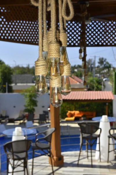 Lámparas decorativas de cuerda en la terraza exterior del Halibut Hotel con zona de piscina al fondo