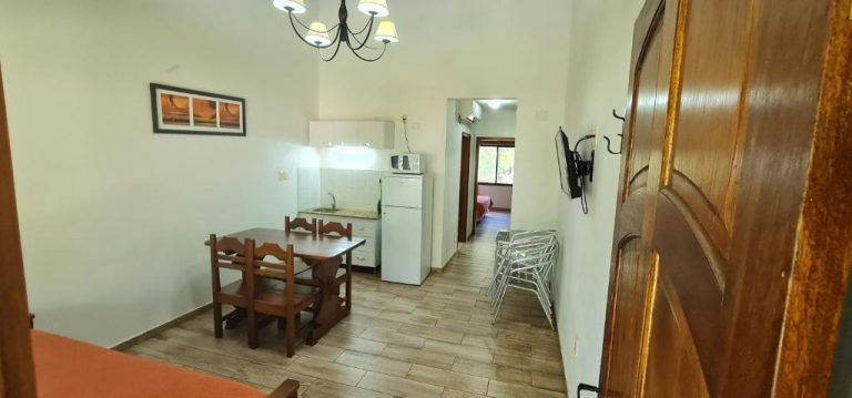Cocina equipada con comedor de madera y nevera en Termas Posada del Siglo XIX