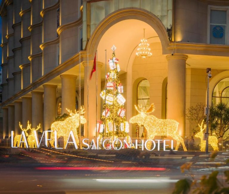 Fachada iluminada con decoración navideña y renos de luces del La Vela Saigon Hotel en Vietnam
