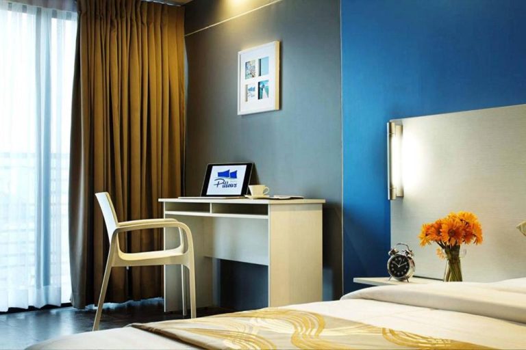Habitación moderna con escritorio, laptop y pared azul en Pillows Hotel Cebu