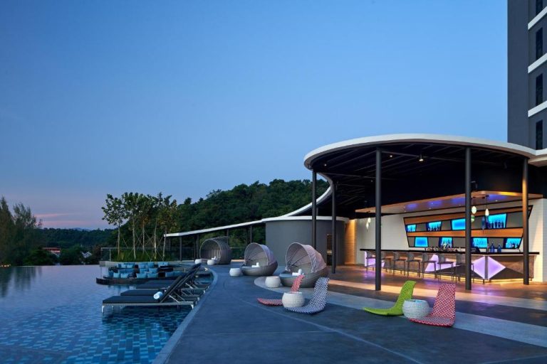 Piscina infinita con bar al aire libre y tumbonas del Aloft Marriott Langkawi Pantai Tengah al atardecer