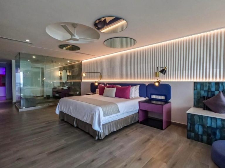 Suite moderna con cama doble, cabecero azul y baño acristalado en Grant's Studio at Mantamar Tower